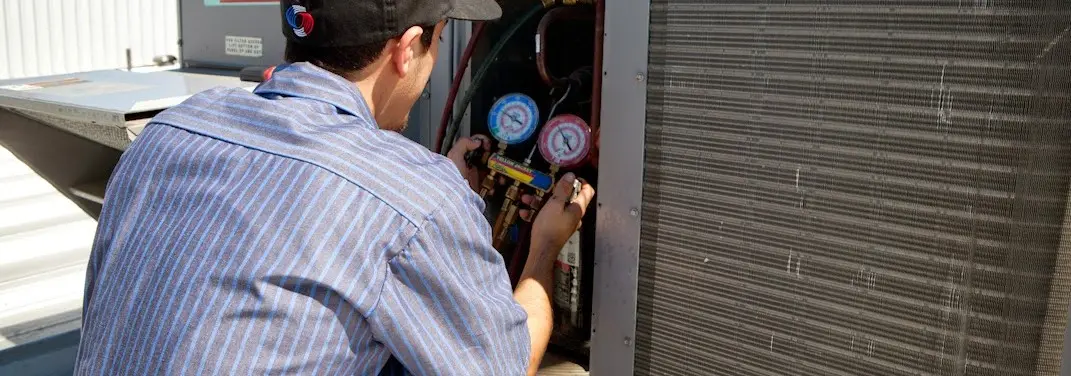 HVAC technician servicing a condenser unit in Makakilo